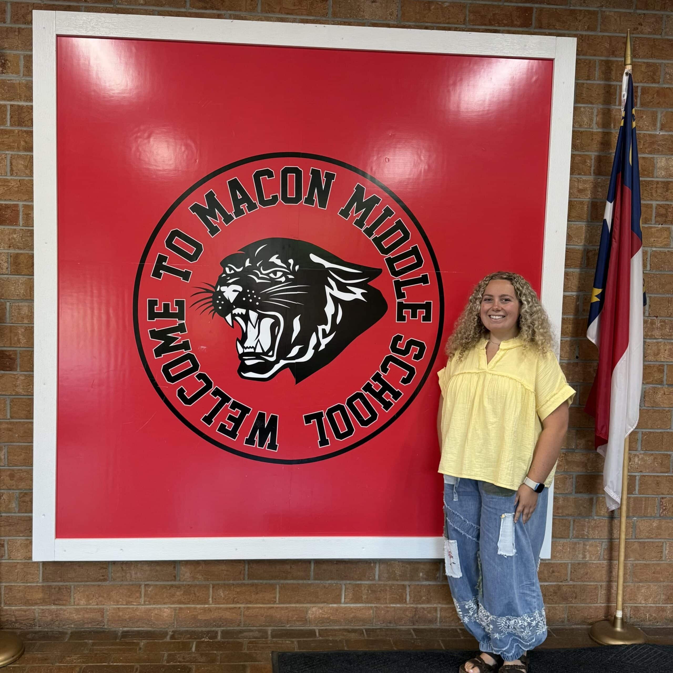 Callie Barnett posing with the "Welcome to Macon Middle School" sign