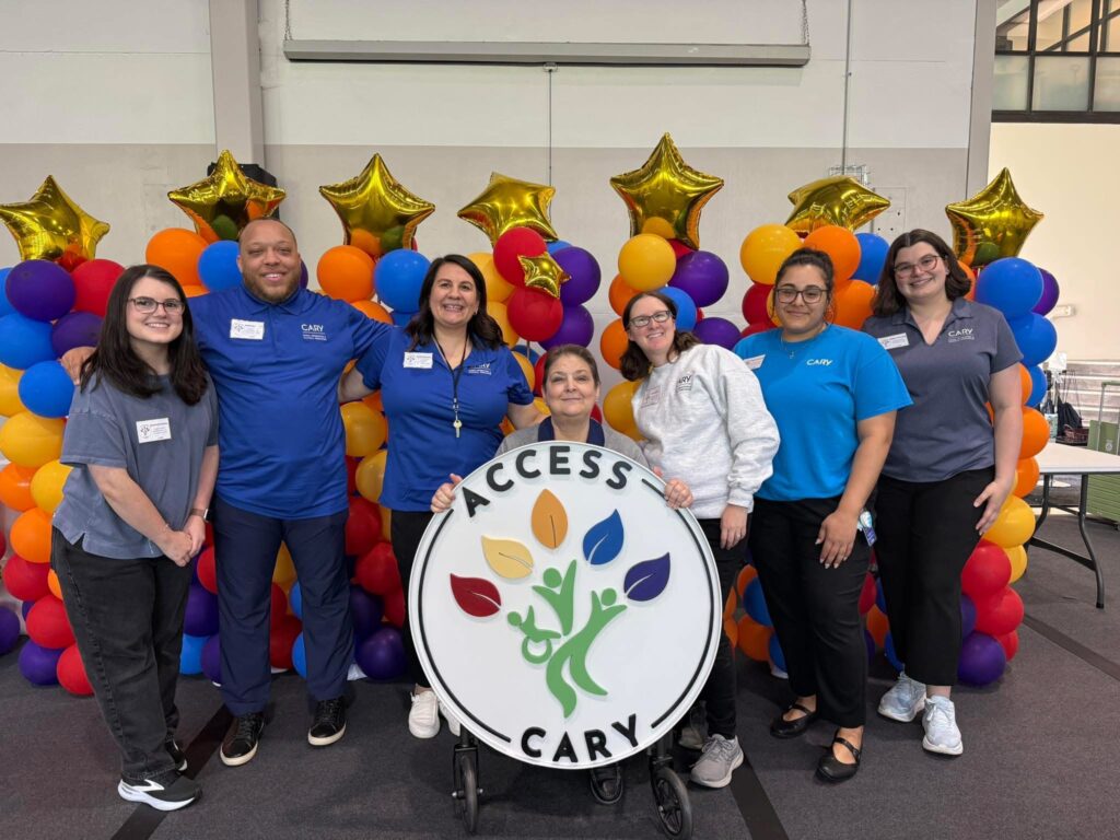 Megan (far right) with ACCESS Cary team posing for a group picture in Cary logo work shirts